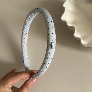 Detail of light blue polka dot headband with handmade label and twill fabric texture
