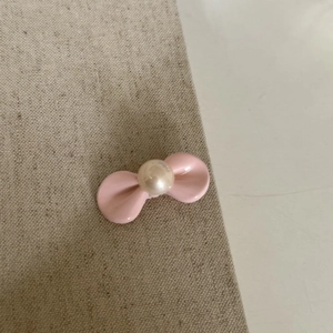 Makroaufnahme der rosa Haarklammer mit Schleife und glänzender Perle in der Mitte