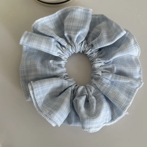 Détail d'un chouchou en tissu vichy bleu clair et blanc avec une texture douce et plissée