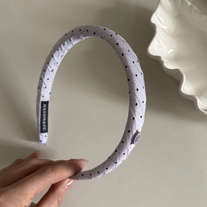 Detail of lavender polka dot headband showing the handmade label and decorative button