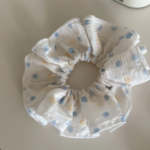 Détail du chouchou blanc avec pois bleus et jaunes et bordures en tissu à volants