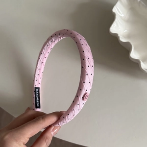 Detail of pink polka dot headband featuring handmade label and decorative button on the side