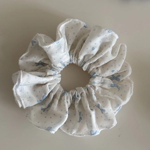 Détail d'un chouchou blanc avec des pois bleus et des motifs de nœuds avec coutures