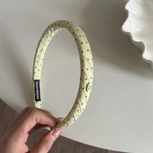 Detail of yellow polka dot fabric headband with decorative handmade label and tag