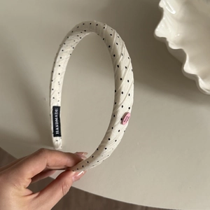 Detail of cream headband with black polka dots featuring a handmade woven label