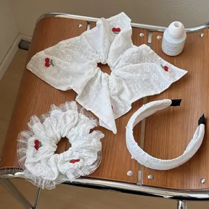 Détail de chouchous en dentelle blanche avec cerises rouges sur une chaise en bois