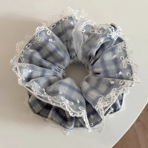 Macro shot of blue plaid scrunchie featuring delicate white lace embroidery details