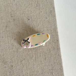 Creamy beige hair clip with colorful polka dots, pink cherry, and black bow detail