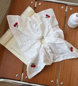 Détail du chouchou en dentelle blanche avec broderies de cerises rouges faites à la main