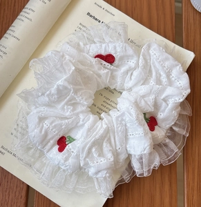 Détail du chouchou en dentelle blanche avec broderie cerise faite main et bordure mesh