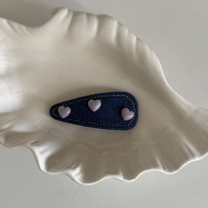 Detail of denim heart BB hair clip with yellow stitching on white ceramic shell