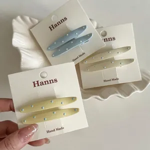 Lot de barrettes à pois bleus et blancs présentées sur un plateau coquillage