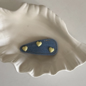 Blue denim fabric heart hair clip with three yellow beads on a white shell plate