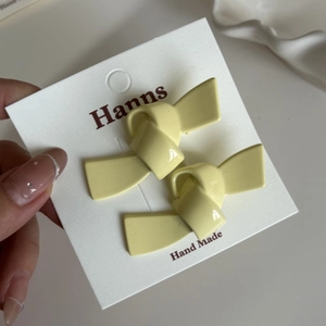Paar hellgelbe Schmetterlings-Haarspangen auf weißer Karte, Nahaufnahme in der Hand