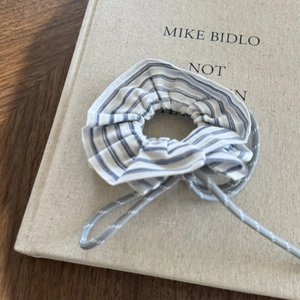 Detail view of a blue and white striped fabric scrunchie with grey cord accent
