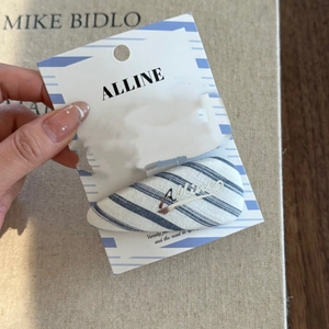 Close-up of a blue and white striped fabric BB hair clip with silver metal lettering