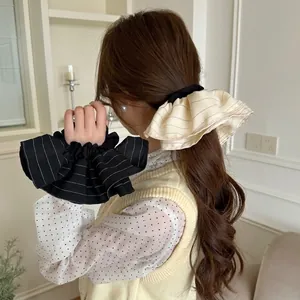 Elegant striped ruffled hair scrunchies in black and beige displayed on a model