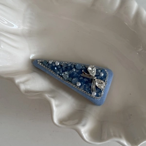 Detail showing blue beaded crystal hair clip with silver butterfly on ceramic tray