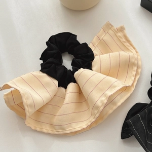Macro shot of oversized ruffled hair scrunchie featuring red stripes on beige woven fabric