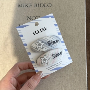 Detail of two striped fabric hair clips with star embroidery on a display card