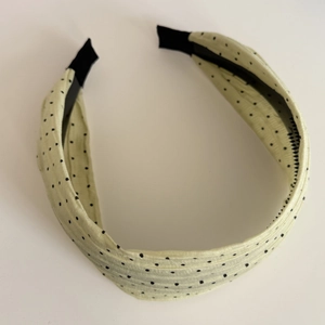 Detail of yellow polka dot pleated headband with black protective end tips on white background