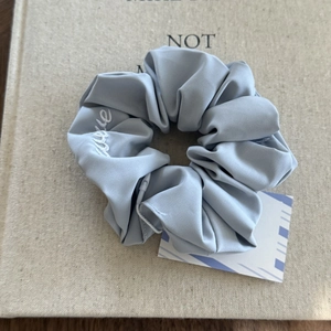 Detail of blue satin scrunchie featuring hidden zipper pocket and love embroidery