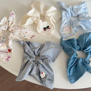 Detail view of blue and patterned bow scrunchies set on white circular background