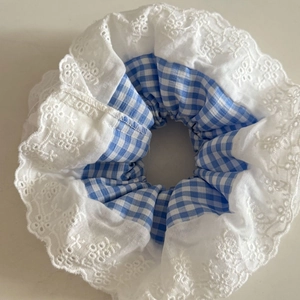 Detailansicht eines blauen Karo-Haargummis mit feiner weißer Spitze und Stickerei