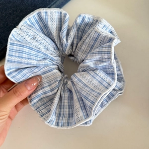 Detailaufnahme von blauem Karo-Haargummi mit zarten weißen Spitzenverzierungen