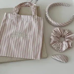 Macro shot of pink striped fabric accessories including headband, scrunchie and clip