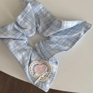 Detail of blue plaid hair scrunchie with pink heart embroidery and lace trim decoration