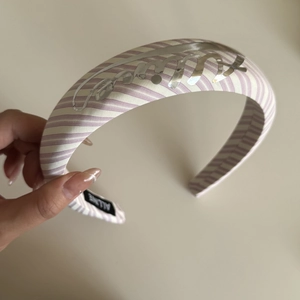 Close-up of a wide pink striped headband with a metallic silver logo and thick padded design