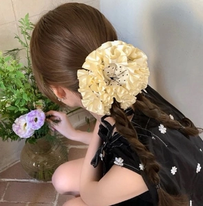 Close-up of cream polka dot ruffle scrunchie styled on double ponytail hair