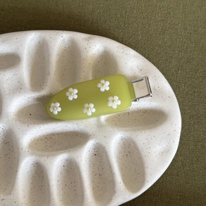Fermaglio per capelli in acrilico verde con fiori di frangipane bianchi su vassoio
