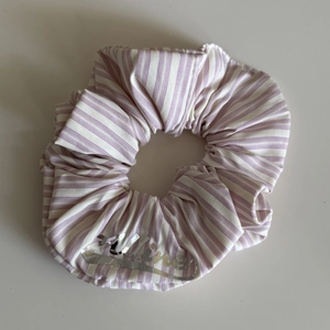 Close-up of a purple and white striped scrunchie with a silver Celine logo detail