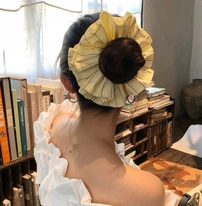 Detail of oversized yellow striped lace scrunchie worn on a high bun hairstyle