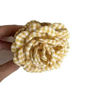Handheld yellow and white gingham fabric flower hair accessory in minimalist retro style