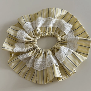 Detail of striped lace fabric scrunchie with delicate floral hollow embroidery