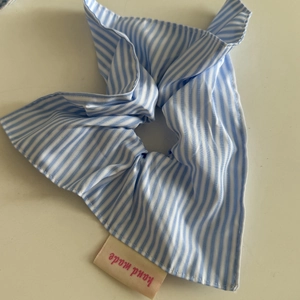 Detailed close-up of blue striped fabric scrunchie with a handmade woven label