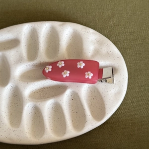 Dettaglio ravvicinato della molletta in resina rosa traslucida con piccoli fiori