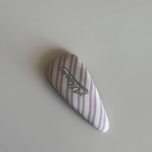 Detail view of the purple and white striped fabric hair clip with Active typography