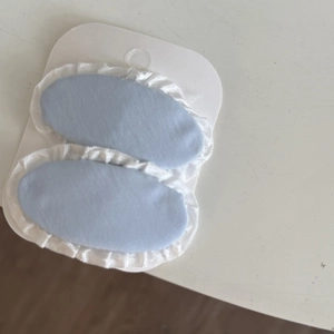 Detail of light blue fabric hair clips with white ruffled edges on display card
