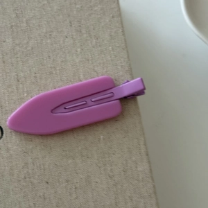 Close-up of a matte purple hair clip on beige fabric for daily hairstyling and makeup