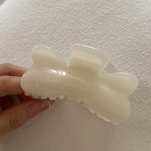 Macro detail of a large cream-colored butterfly claw clip made of glossy resin material