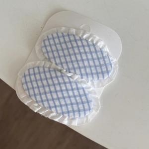 Detail view of blue gingham hair clips with white lace trim on card packaging