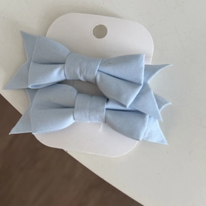 Close-up of light blue fabric bow hair clips with textured weave on display card