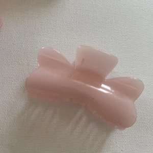 Detail view of pink bow-shaped hair claw clip with glossy finish and durable resin teeth