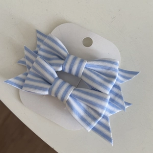 Detail of blue and white striped fabric bow hair clips set on a display card