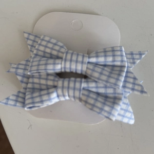 Close-up of a pair of blue and white checkered bow hair clips on display card