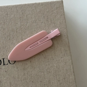 Detail of a matte light pink duckbill hair clip with matching color painted metal base